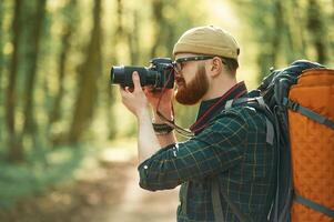 Professional,, photographer. Bearded man is in the forest at daytime photo