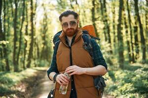 Enjoying warm, weather and nature. Bearded man is in the forest at daytime photo