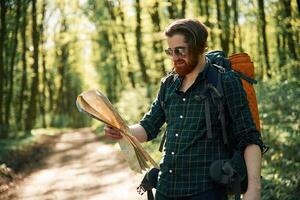 Using ,,the map. Bearded man is in the forest at daytime photo