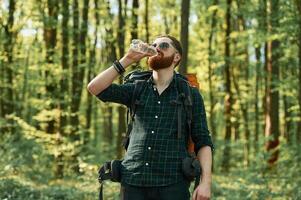 In ,cool sunglasses. Bearded man is in the forest at daytime photo