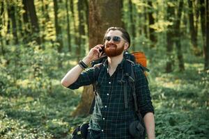 Phone ,in hand. Bearded man is in the forest at daytime photo