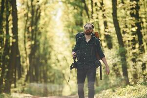 On the,, pathway with binoculars. Bearded man is in the forest at daytime photo