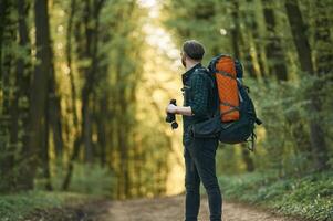 On, the pathway with binoculars. Bearded man is in the forest at daytime photo