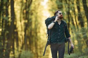 Smartphone in, hand. Bearded man is in the forest at daytime photo