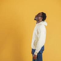 In glasses, looks to the copy space. Black guy is against yellow background photo