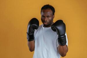 Conception of strength... In boxing gloves. Black guy is against yellow background photo