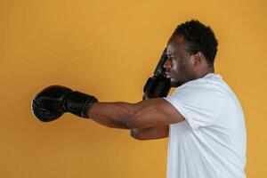 Practicing the boxing punch. Black guy is against yellow background photo