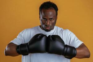 Conception,, of strength. In boxing gloves. Black guy is against yellow background photo