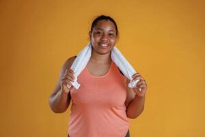 With white, towel, after, exercise. African American woman is in the studio against yellow background photo