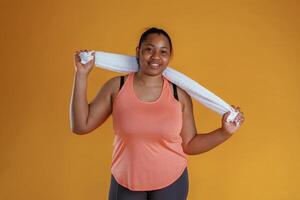 With white ,towel, after exercise. African ,American woman is in the studio against yellow background photo
