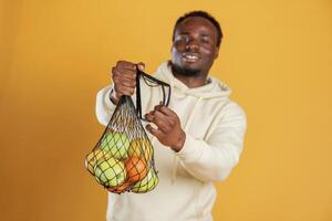 Many,, of the fruits in the bag. Black guy is against yellow background photo