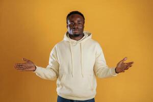 Cheerful ,black ,guy is against yellow background with opened arms photo