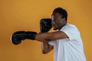 Practicing the boxing ,punch.. Black guy is against yellow background photo