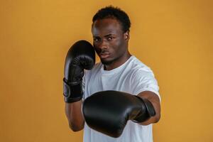 Conception of, strength. In boxing gloves. Black guy is against yellow background photo