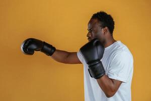 Practicing t,he, boxing punch. Black guy is against yellow background photo