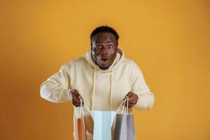 What's, in the bag. Shocked and surprised. Black guy is against yellow background photo
