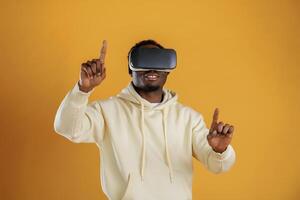 Playing VR, game. In virtual reality glasses. Black guy is against yellow background photo
