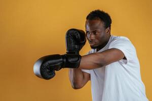 Practicing the boxing punch.. Black guy is against yellow background photo