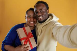 Making, selfie. Happy black couple are together against yellow background photo