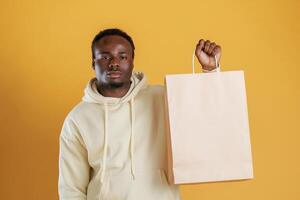 Bag, with copy space, conception of shopping. Black guy is against yellow background photo