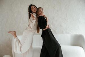 Standing and embracing each other. Two happy young female best friends are indoors. photo