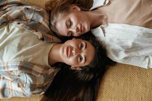 Lying down on the floor. Two happy young female best friends are indoors photo
