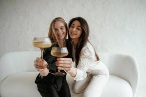 In black ,and white ,clothes,, with drink, celebrating. Two happy young female best friends are indoors photo