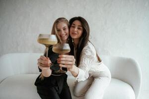 In black, and ,white clothes, with drink, celebrating. Two happy young female best friends are indoors photo