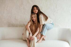 Front view, mmsitting. Two happy young female best friends are indoors photo
