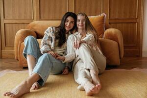Front view, sitting. Two happy, young, female best friends are indoors photo