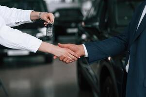 Close up view of woman giving keys of new car to the businessman... photo