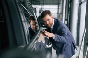 Embracing new automobile. A businessman, is in a car dealership photo