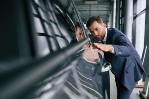 Embracing ,,new automobile. A, businessman is in a car dealership photo