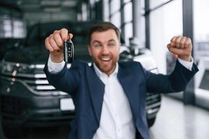 Happy new owner ,of,, automobile. A businessman is in a car dealership photo