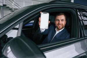 Smartphone, with copy space on display. Businessman is in the brand new car,, photo