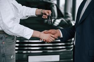 Close, up, view of woman giving keys of new car to the businessman photo