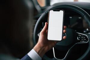 Smartphone with copy space on display.. Businessman is in the brand new car photo