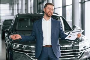 With notepad,,. A businessman is in a car dealership photo