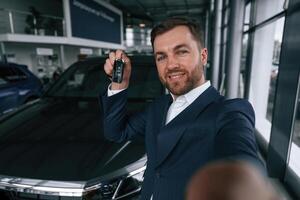 Happy new owner of automobile.. A businessman is in a car dealership photo