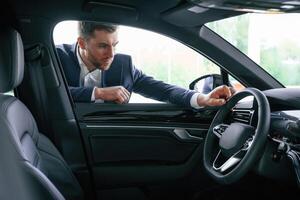 Looking at, the, automobile. A businessman is in a car dealership photo
