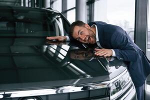 Embracing new, automobile. A businessman is in a car dealership photo