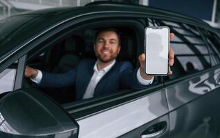 Smartphone with, copy space on display. Businessman is in the brand new car photo