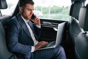 Working, using ,laptop. Businessman is in the brand new car photo