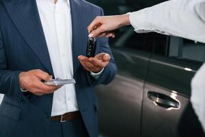 Close, up view of woman giving keys of new car to the businessman photo