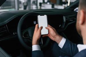 Smartphone, with copy space on display. Businessman is in the brand new car.. photo