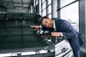 Embracing, new automobile. A businessman is in a car dealership photo
