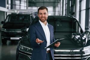 Cheerful, salesman. Guy is in a car dealership photo