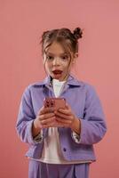 Surprised, using smartphone. Cute little girl is against pink background,, photo