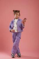 Focused by using smartphone. .Cute little girl is against pink background photo