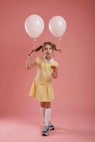 Showing tongue, playful, with balloons. Cute little girl is against pink background photo